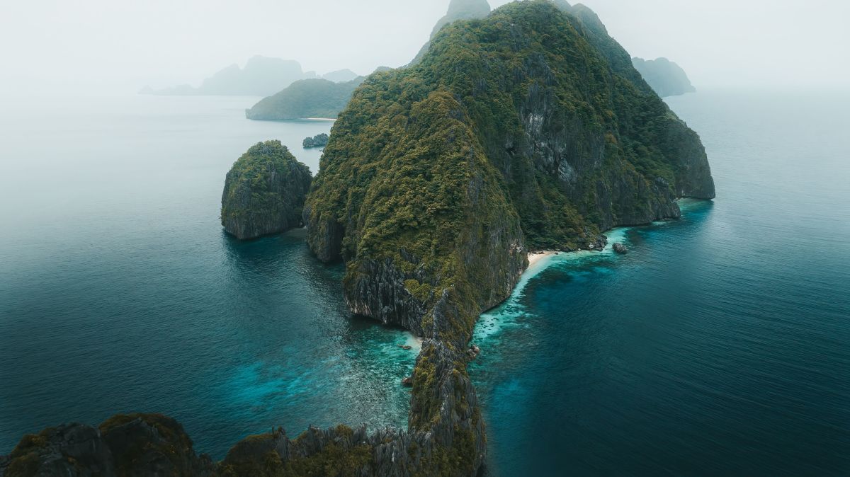 Aerial view of a lush green island with limestone cliffs in Palawan, Philippines