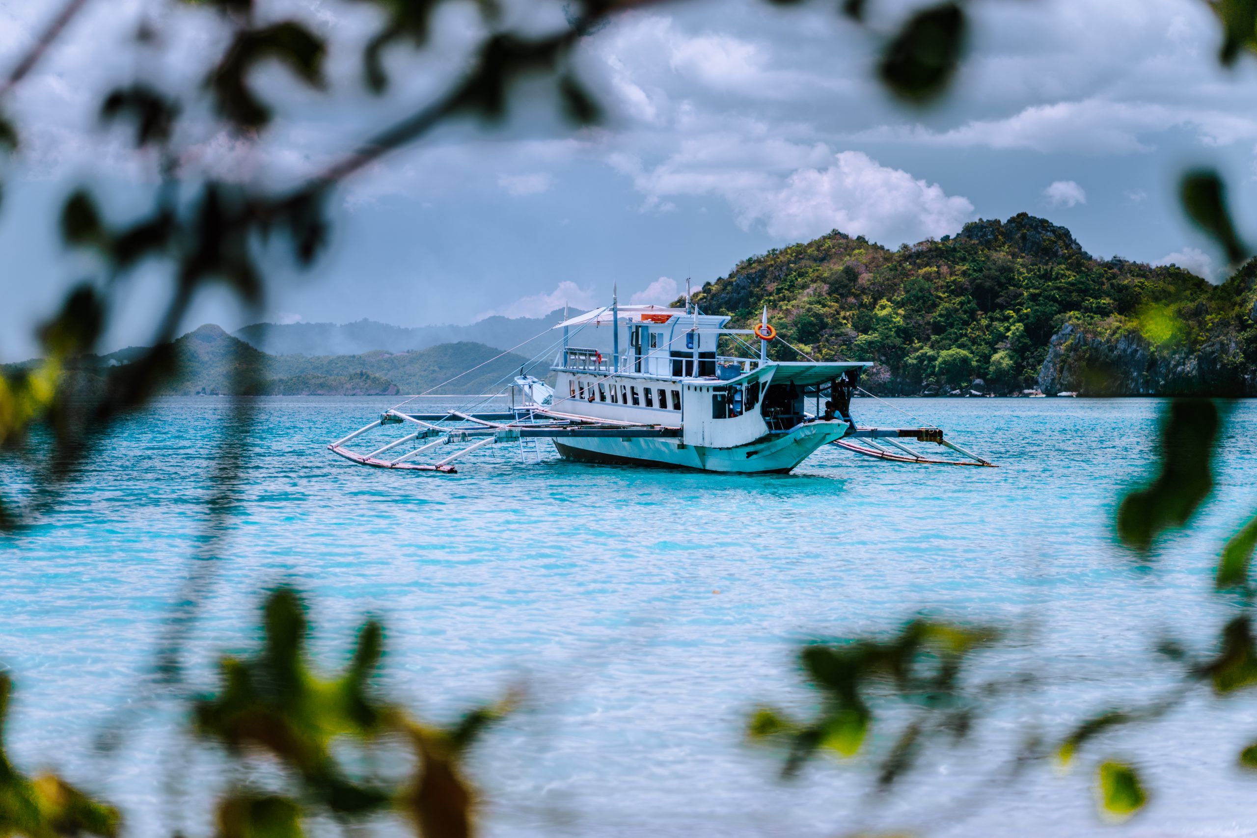 Touring boat floating in the turquoise waters of Cadlao Lagoon, El Nido