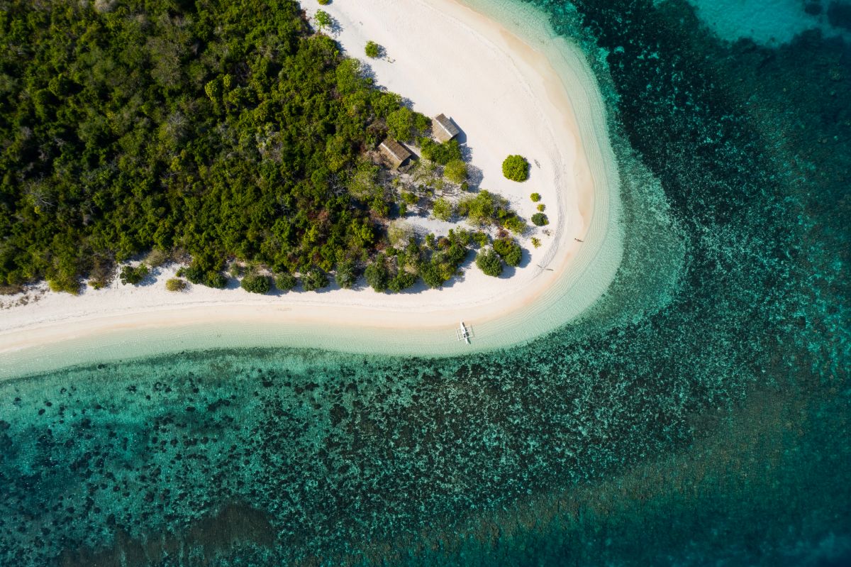 Secluded beach in Coron, Palawan surrounded by lush greenery and clear blue water